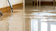 © A2Z AI  - Indoor flooding aftermath: brown water covers the floor, reflecting the walls and light. A ladder is partially submerged. A troubling scene of water damage and potential loss.