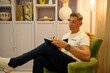 © Cristian Blázquez - Man writing in notebook relaxing in armchair