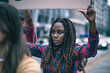 © Lomb - Young woman participates in protest holding a sign in a busy city street during the day
