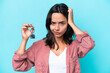 © luismolinero - Young hispanic woman holding home keys isolated on blue background having doubts