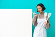 © luismolinero - Young mixed race cook woman with a big placard isolated on blue background showing ok sign with fingers
