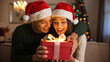 © Rony - Happy Couple Exchanging Christmas Gift with Glowing Box and Festive Tree Lights