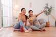 © Kiattisak - Asian women enjoying wellness lifestyle at home after workout, sitting on floor with apples and water bottles, healthy habits, friendship, clean eating, and relaxation.