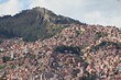 © Koapan - Densely built-up, steep mountainside in Bolivian capital La Paz with countless unfinished brick buildings. Original vegetation was pushed back by humans onto rocky mountain peaks. Wealth meets poverty