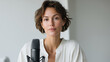 © Anastasiia Havelia - woman standing behind podcast microphone in clean studio, minimal background, calm confident expression, professional preparation mood, editorial lighting,