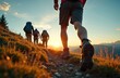 © Vadym - Group of hikers walks on mountain trail at sunset. Active tourists with backpacks trekking in mountains. Team climbs to peak on summer vacation. Travel adventure lifestyle concept. Exploring outdoors.