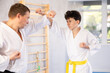 © JackF - Active teen male karate practitioner training battling methods with middle-aged partner in sports hall