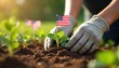 © Vadym - Gardener plants seedling with American flag in fertile soil. Hands in gloves nurture green plant. Outdoor hobby cultivation, patriotism symbols, summer day. Growth, nature care.