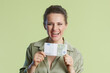 © Alliance - A smiling woman holds a 100 Euro bill. Light green blouse, light green backdrop convey financial success and joy with soft lighting.