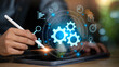 © chaylek - A businessman using a digital tablet with glowing gear icons, representing workflow automation, business process management, innovation, and efficiency powered by modern digital technology.