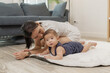 © kamiphotos - A baby enjoys tummy time on a soft mat while the mother stays close, encouraging him with a warm smile. This tender moment highlights early development, family care, and bonding at home.