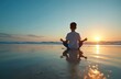 © Maryna - Young boy meditates on sandy beach at sunset. He sits in lotus position practicing mindfulness near calm ocean waves. The scene conveys peace and concentration during golden hour.