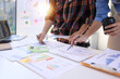 © SOMKID - Business person hands working with business financial graph data and marketing plan at desk in office, Business people meeting explaining and business concept.