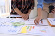 © SOMKID - Business person hands working with business financial graph data and marketing plan at desk in office, Business people meeting explaining and business concept.