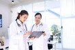 © SOMKID - Two medical doctors woman checking the patient papers in  hospital, Medical technology and Healthcare concept.