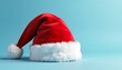 © cd - Iconic Santa Claus hat with soft red fabric and fluffy white trim displayed on a blue background during the festive season, created with generative ai