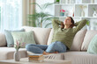 © Antonioguillem - Woman in green relaxing on a couch at home