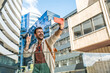 © Srdjan - Young traveler laughing while taking a selfie in a modern business district cheerful millennial man with backpack capturing urban architecture and city vibes on smartphone during a sunny day