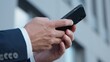 © Yuliia - Close-up male hands holding mobile phone in city unrecognizable business man chatting with smartphone device unknown businessman with cellphone sending sms message using online cyberspace internet