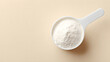 © utaem2022 - White powder in a measuring scoop on a soft beige background with copy space for design