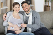 © auremar - young couple with pregnant woman holding baby shoes together
