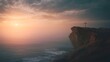 © slonme - Serene sunrise over a misty ocean, with a solitary cross silhouetted on a rugged cliff.