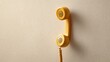 © olga_demina - Yellow old fashioned telephone handset hanging on a simple textured wall, representing vintage communication, connection, and nostalgia with ample copy space