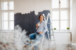 © Halfpoint - Beautiful woman painting walls of her new apartment by herself.
