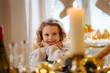 © Halfpoint - Cheerful small girl indoors at home at Christmas, looking at candle.