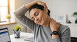 © Atmospheres - Relaxed woman stretching her neck at her office desk to relieve pain and stress during a work break, practicing workplace wellness and ergonomics.