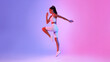 © Prostock-studio - A fit woman in activewear executes an elbow-to-knee crunch with focus and energy. The striking pink and blue background enhances the dynamic atmosphere of her workout.
