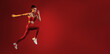 © Prostock-studio - A young woman in athletic wear leaps forward with determination against a solid red backdrop. Her focus and movement highlight the energy and strength of her workout.