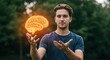 © CrazyJuke - Brainwave in Hand: A thoughtful man stands in the outdoors, holding a glowing brain symbol, representing the power of thought and the wonders of the mind.