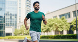 Smiling man actively running in modern city environment.