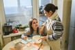 © o_lypa - Woman and her daughter preparing dough for Christmas cake in kitchen.