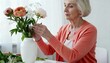 © Anna - Elegant senior woman arranging a bouquet of fresh peonies in a vase. Elderly lady enjoying her floristry hobby at home. Retirement lifestyle and creative pastime