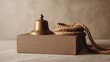 © Line - Bronze bell with thick rope on cardboard box in neutral setting