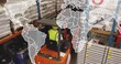 © vectorfusionart - Operating forklift driver in yellow vest, hard hat navigating warehouse with pallets, drums, board