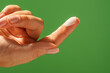 © kinomaster - A close up of a woman hand with fingers folded, holding cream on one fingertip against a vibrant green background. Beauty concept, skin care, and cream product presentation.