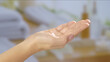 © kinomaster - Close up of an open hand holding a small amount of cream, set against a blurred spa like background. Beauty concept, skin care, and cream product presentation.