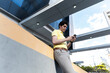 © Rendara Studio - Entrepreneur checking smartphone while leaning on urban structure