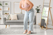 © Pixel-Shot - Young overweight woman in tight jeans at home