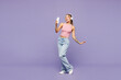 © ViDi Studio - Full body young happy woman wear pink tank top casual clothes listen to music in headphones use mobile cell phone isolated on plain pastel light purple background studio portrait. Lifestyle concept.