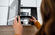 © M-Production - Woman placing a plate of food into the microwave.
