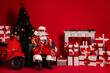 © deagreez - Santa sits in a red room with a coffee mug surrounded by gifts a Christmas tree and a red scooter
