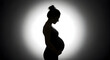 © mamo studios - Pregnant woman silhouette against a dramatic backlit background, showcasing maternity, new life, hope, and the tender connection of motherhood as she gently holds her belly.