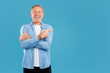 © Prostock-studio - Mature man expressing excitement while pointing to the side, encouraging others to notice the empty space for advertisement. He stands against a solid blue backdrop, smiling brightly.