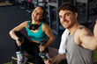 © Home-stock - Sporty couple sitting in gym, smiling and posing for selfie, both holding dumbbells, appear happy and engaged in their fitness routine