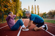 © Drazen - Happy mature athlete assisting his wife in doing sit-ups during outdoor workout in autumn.