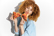 © VICHIZH - Young woman enjoying delicious pizza slices, showcasing a playful and carefree mood against a bright white background